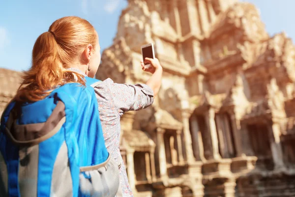 Young female tourist with smartphone in Angkor Wat, Cambodia