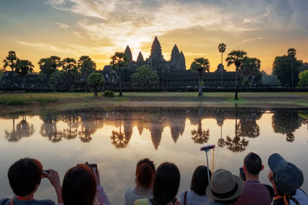 Many Asian tourists taking picture of Angkor Wat at sunrise