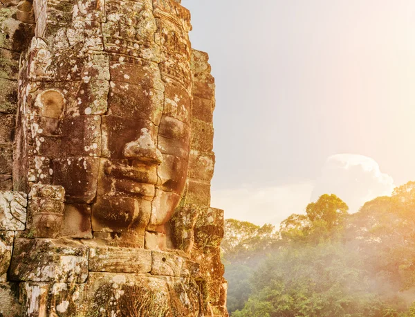 Enigmatic giant stone face of Bayon temple in evening sun