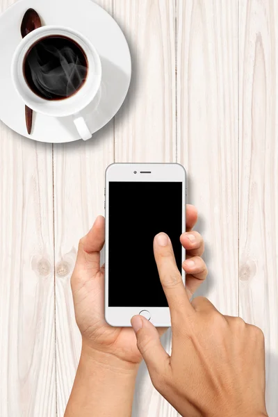 Hand holding and Touch on White Smartphone with coffee table