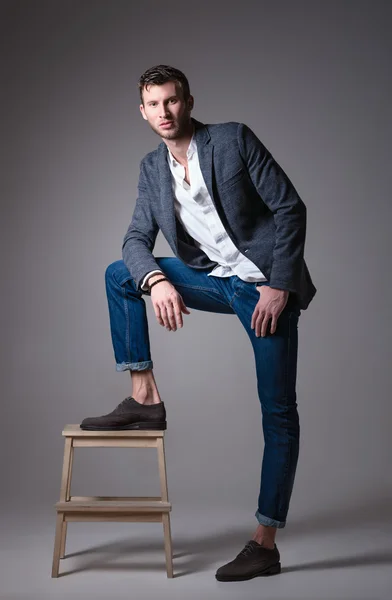 Studio fashion shot: portrait of handsome young man wearing jeans, shirt and jacket