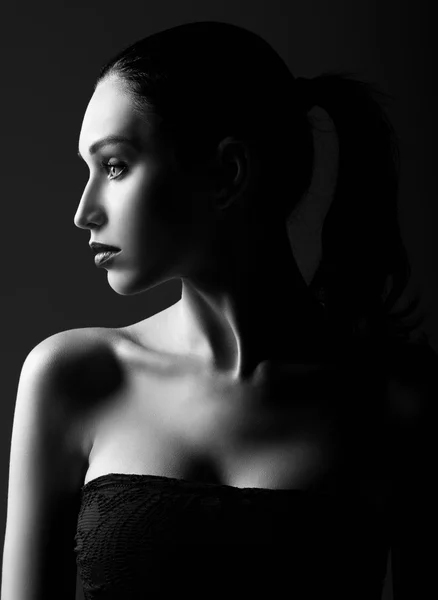 Studio shot: dramatic portrait of beautiful young woman. Profile view. Black and white