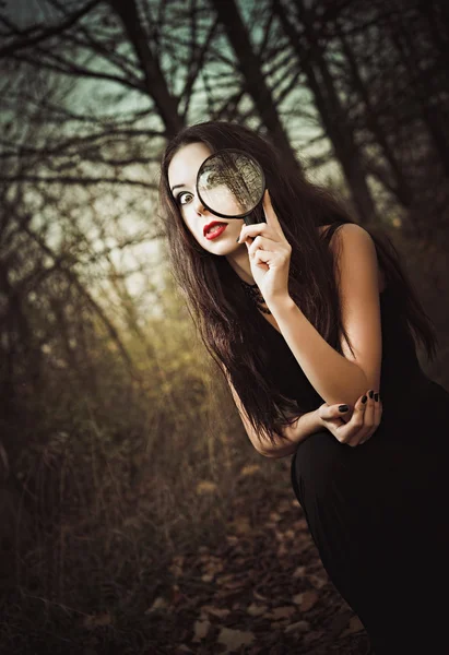 Strange goth girl looks through loupe