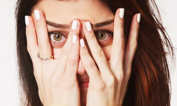 Young woman peeking through fingers (Symbol fraud in business and politics)