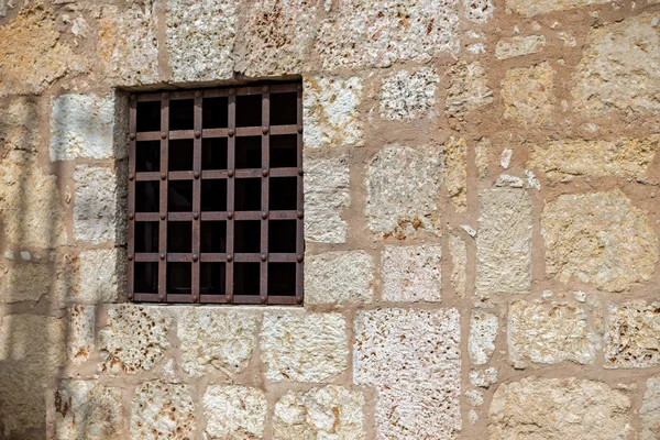Window with rusty iron bars at a stone wall
