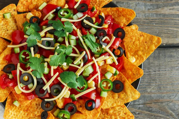 Mexican tortilla chips with cheese tomato black olives pepper sauce