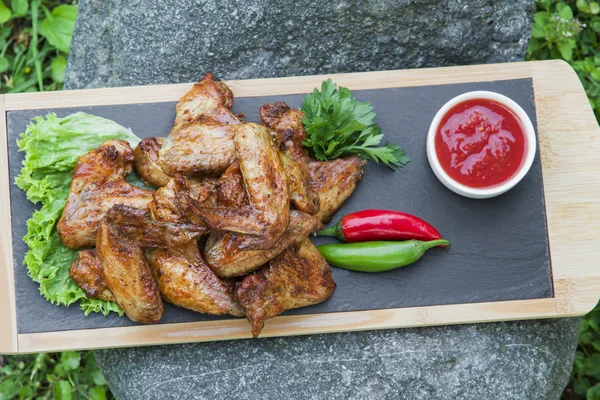 Grilled chicken wings in nature on a rock