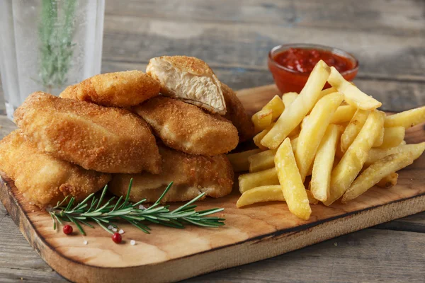 chicken nuggets french fries on the board with red sauce