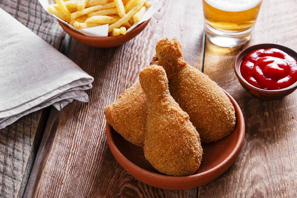 Fried chicken leg in breadcrumbs and french fries