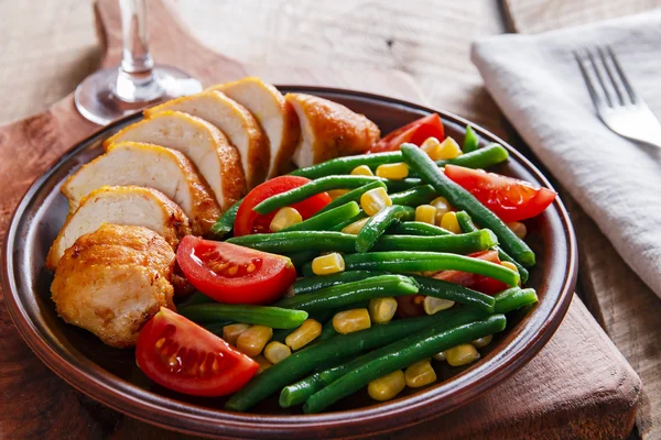 Grilled chicken breast  with green beans and tomato on a plate