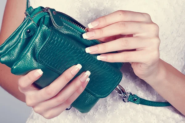 Female hands with manicure with green handbag
