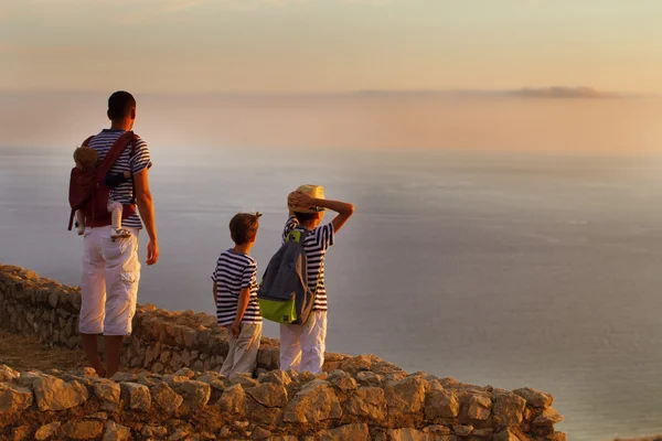 Father with children watching  sunset on top of mountain