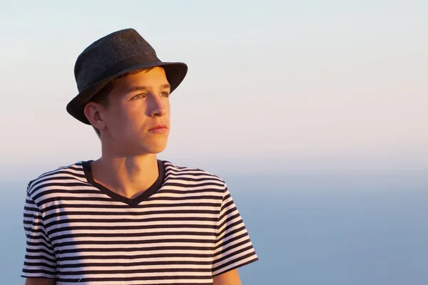 Portrait of serious and pensive young man on sunset sky background