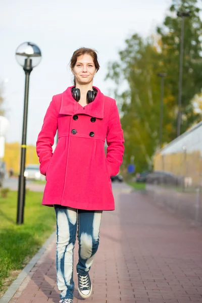 Beautiful woman in red coat walking autumn street.