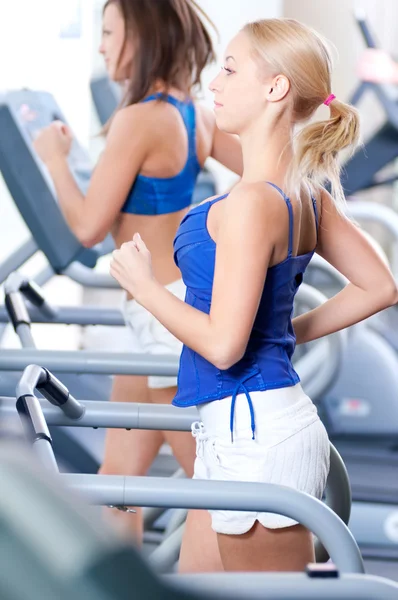 Women run on machine in gym