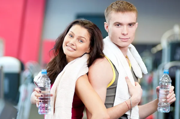 Man and woman drinking water in gym