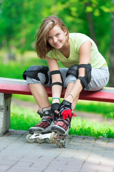 Girl putting on inline skates on bench