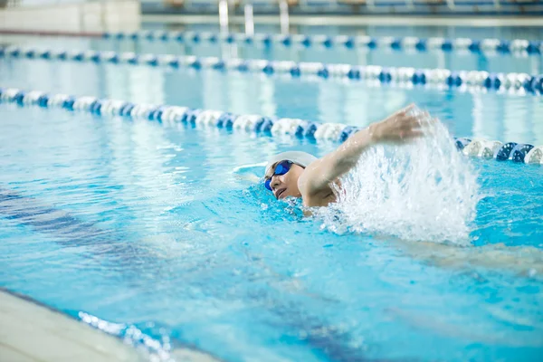 Young girl in goggles swimming front crawl stroke style