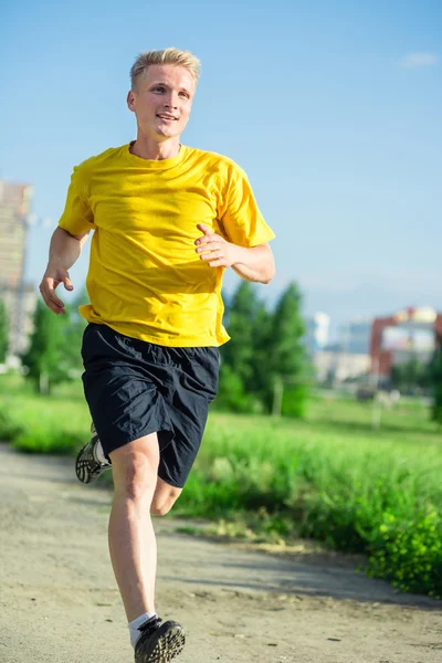 Sporty man jogging in city street park. Outdoor fitness.