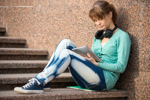 Beautiful young woman student with note pad and headphones. Outdoor student.
