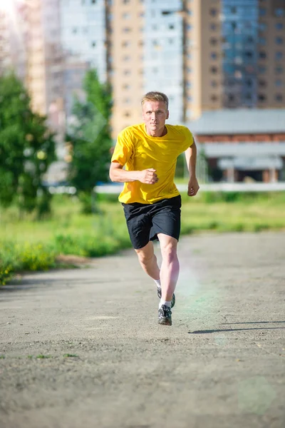 Sporty man jogging in city street park. Outdoor fitness.