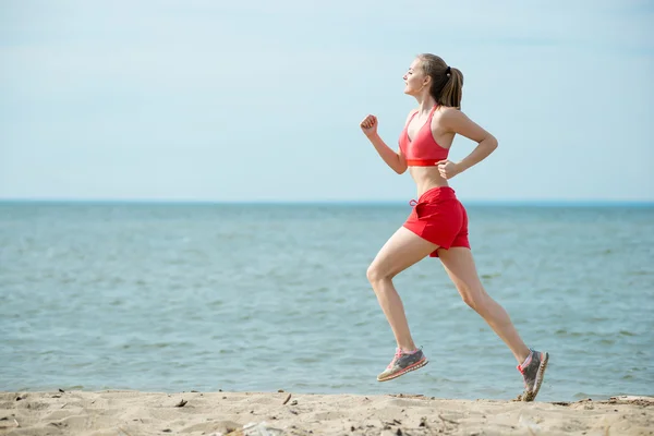 Young lady running at the sunny summer sand beach. Workout.  Jog