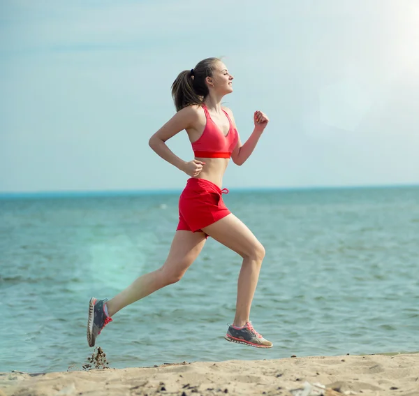 Young lady running at the sunny summer sand beach. Workout.  Jog