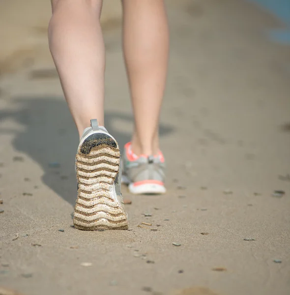 Sport footwear, sand footprints and legs close up. Runner feet d