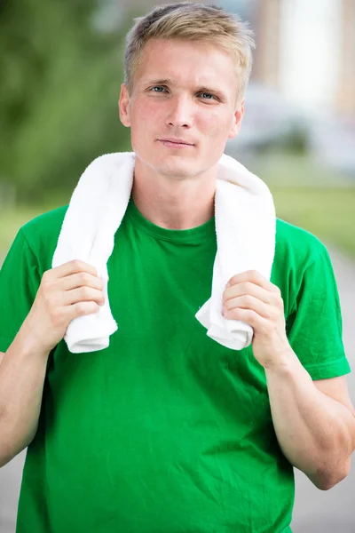 Tired man after fitness time and exercising. With white towel