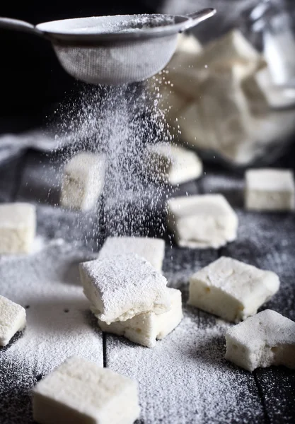 Marshmallows sprinkled with sugar powder from sieve