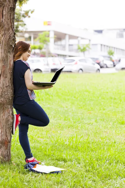 Student girl using a laptop computer near a tree