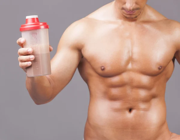 Muscular man holding a shaker with protein