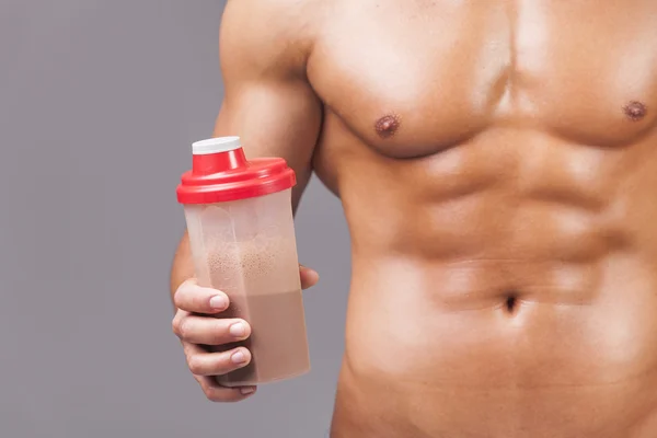 Muscular man holding a shaker with protein