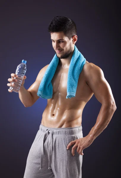 Fitness man holding a bottle of fresh water on black background