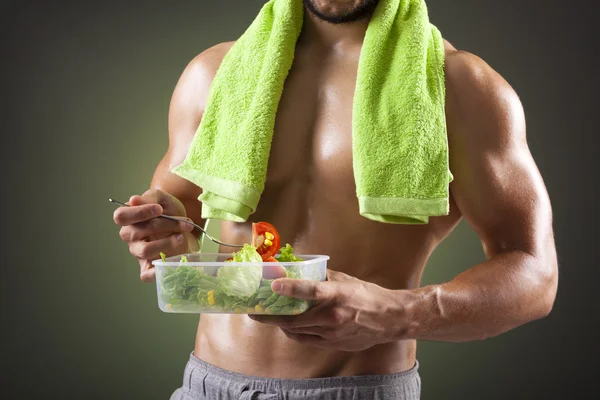 Fitness man eating salad