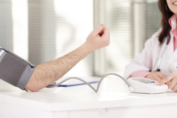 Female doctor checking man blood pressure
