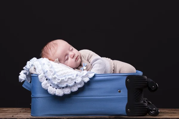 Newborn baby sleeping inside trolley bag
