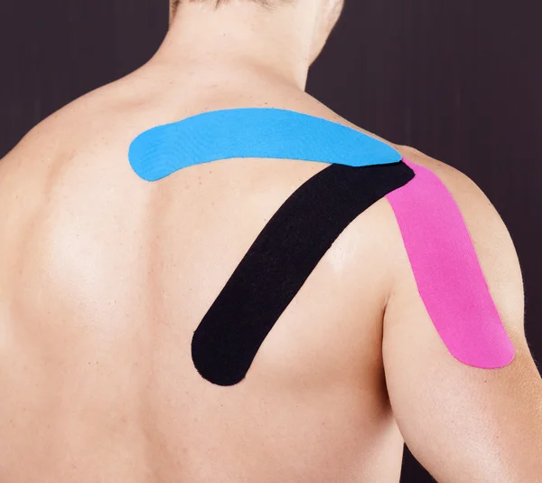 Muscular man with kinesiotaping on the shoulder