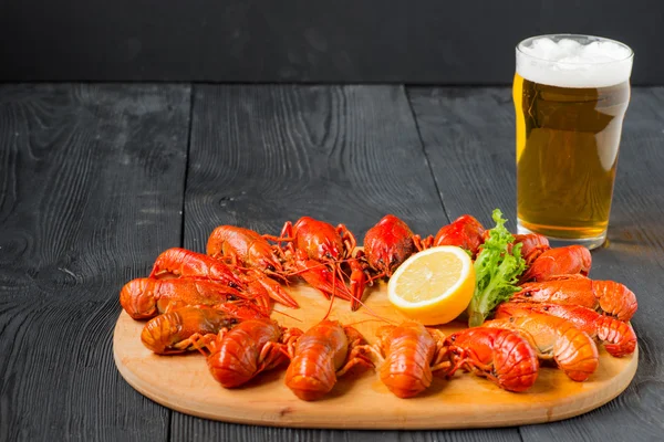 Boiled red crayfishes on a wooden cutting board and beer glass