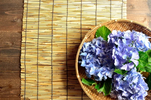 Blue hydrangea in the bamboo basket on bamboo blind background