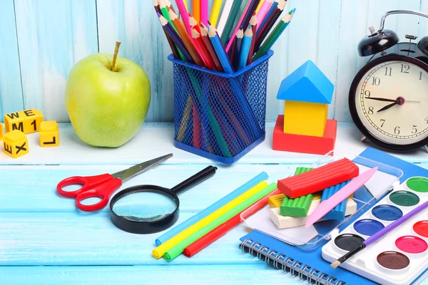 School supplies pencils crayons colorful assortment wooden background gentle blue tone