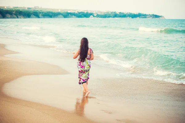 Rear view of child walking along the seacoast.