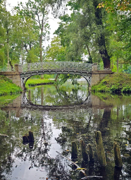 Picturesque landscape with old bridge over flow in the park