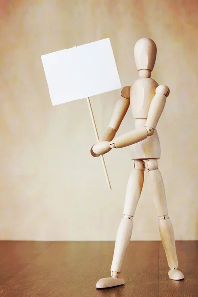 Wooden human model holding blank white poster. Concept of demands