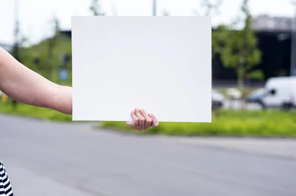 Woman outside with a blank white card