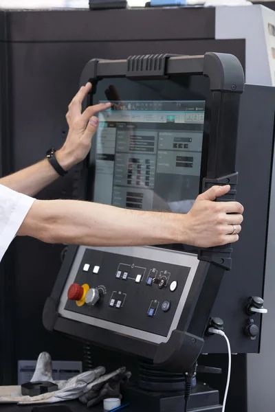 Engineers hand on working computer panel of CNC machine