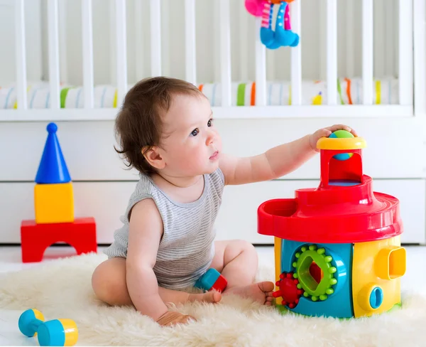 Baby girl playing with educational toy in nursery