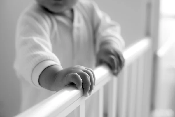 Baby hand holding on to the bed