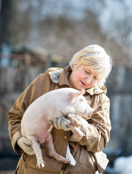 Happy woman holding  newborn piglet