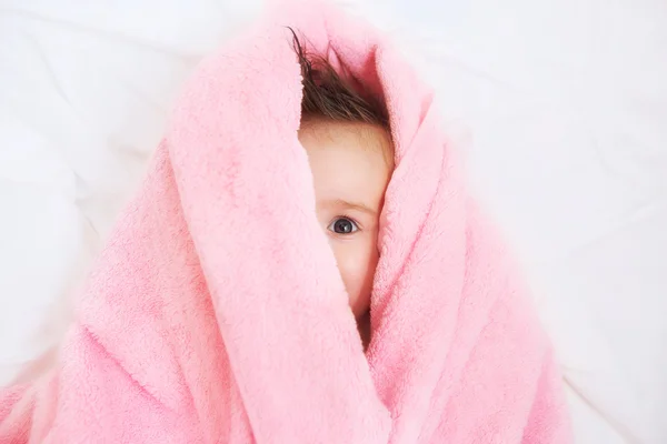 Happy little baby hidden in white towel after bath